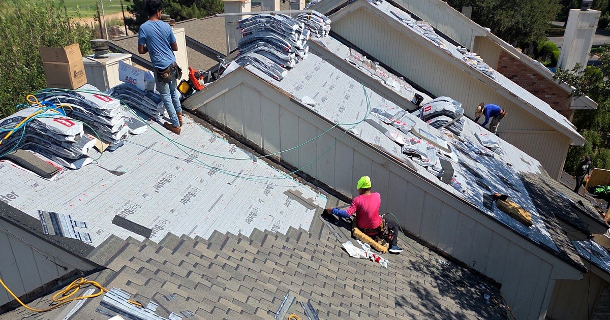 A professional roofer, acting as a certified contractor, is skillfully installing shingles on a residential roof, ensuring compliance with industry standards for a reliable roofing system. This meticulous roof installation is crucial for maintaining the roof's condition and protecting warranty coverage against potential material defects.