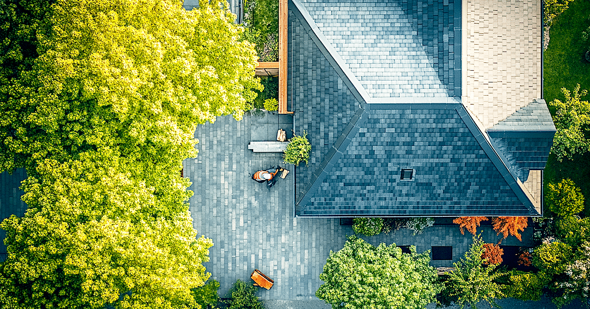 A professional roofer is carefully examining the installation quality of a new asphalt shingle roof using measuring tools to check alignment and ensure it is installed correctly. This attention to detail is crucial for preventing premature roof failure and maintaining the roof's lifespan.