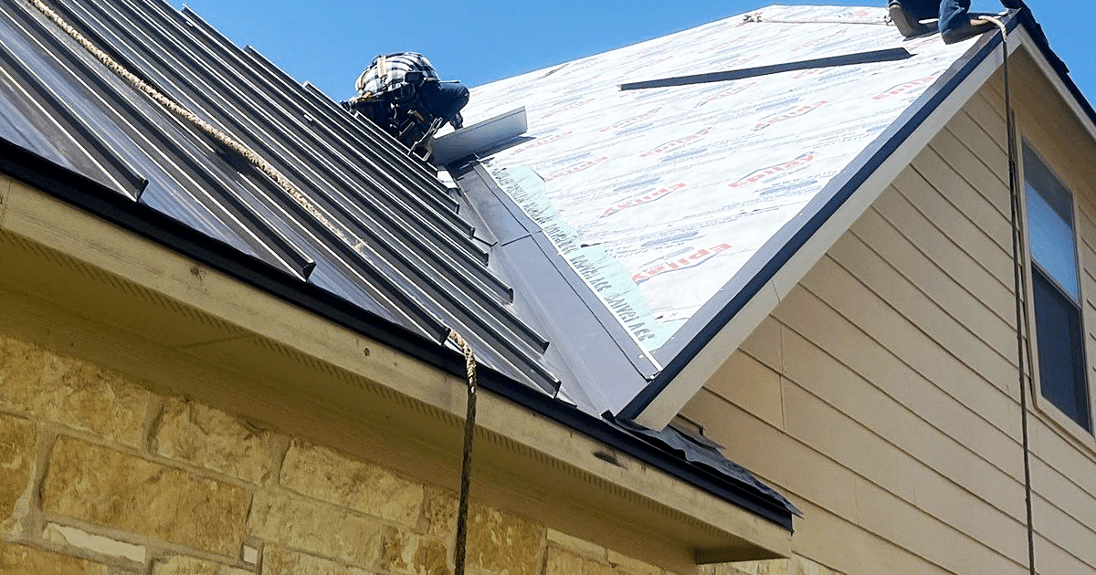 A professional roofing contractor is installing metal flashing around a roof vent on a sunny day, ensuring proper installation to prevent leaks and protect the underlying roof structure. This critical step in the roofing system helps direct water away from vulnerable areas and maintains the roof's integrity.