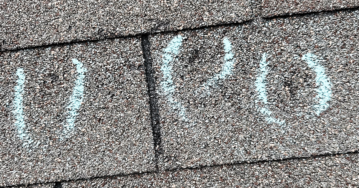 The close-up image shows hail-damaged asphalt roof shingles, highlighting visible granule loss and a few missing shingles. This damage serves as a reminder for Texas homeowners about the importance of timely roof maintenance to prevent costly repairs and maintain the roof's lifespan.