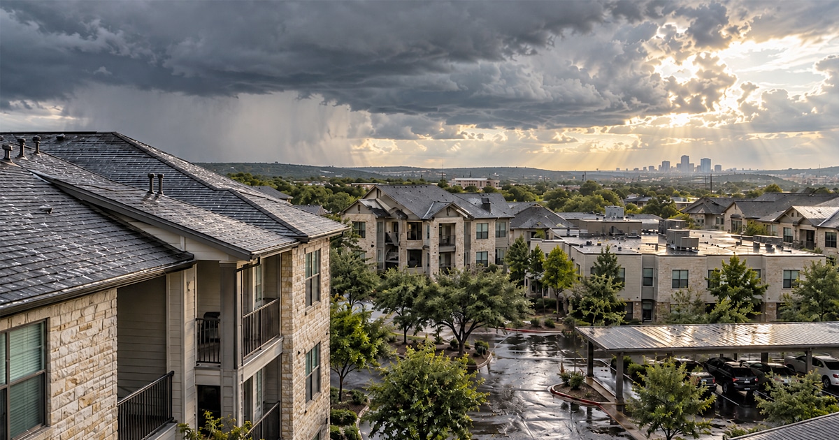 Multifamily apartment community after a hailstorm with wet rooftops, storm clouds, and clearing skies.